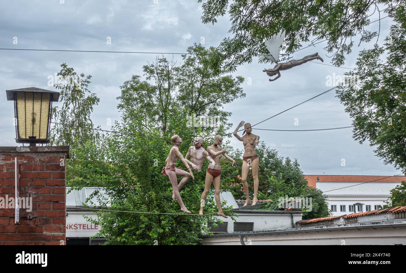 Germany, Lubeck - July 13, 2022. 4 monokini clad Caucasian fashion dolls standing on cords hanging from trees as art project on Wallstrasse under clou Stock Photo