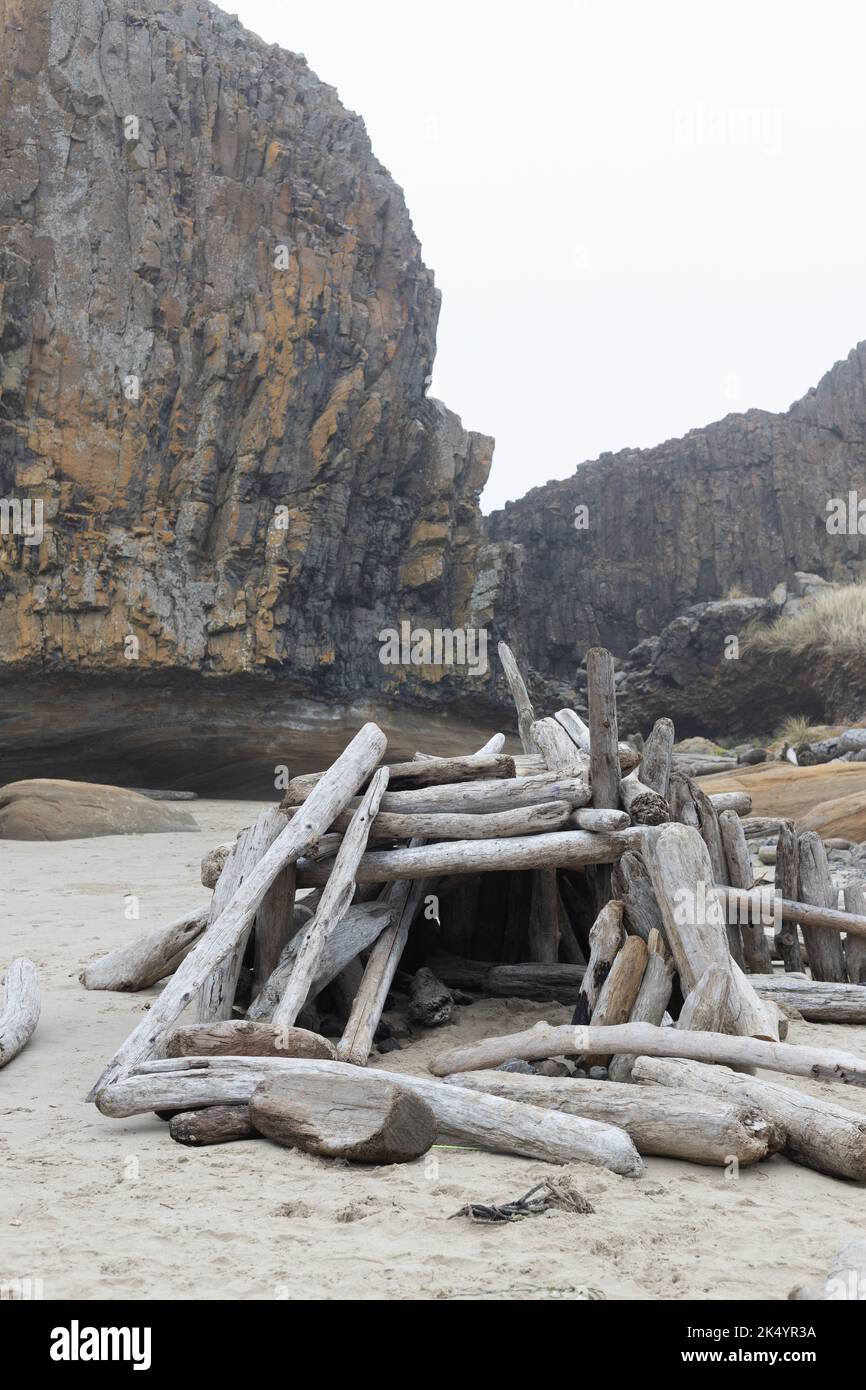 A driftwood structure and a rock formation at Seal Rock State Park