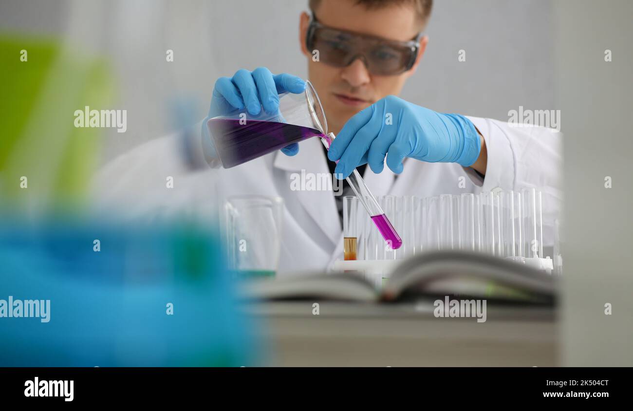 Scientist in protective gloves holding test tube of purple liquid Stock Photo
