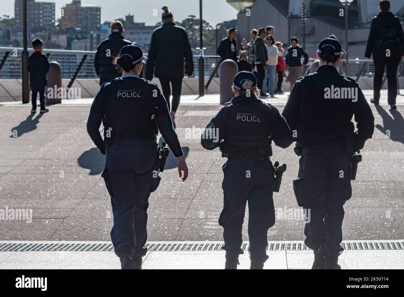 Three New South Wales Police officers on morning foot patrol, carrying side arms, walk around the forecourt of the Sydney Opera House in Australia Stock Photo