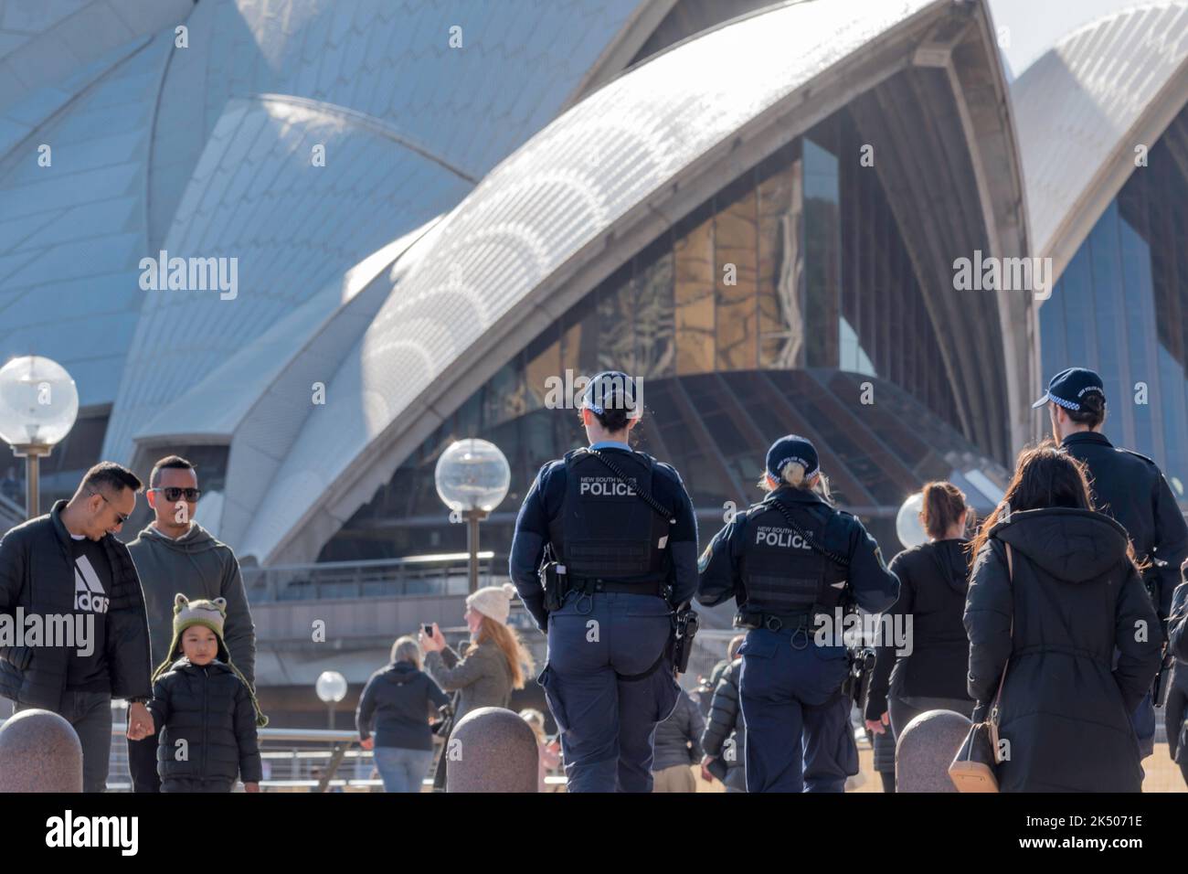 Three New South Wales Police officers on morning foot patrol, carrying side arms, walk around the forecourt of the Sydney Opera House in Australia Stock Photo