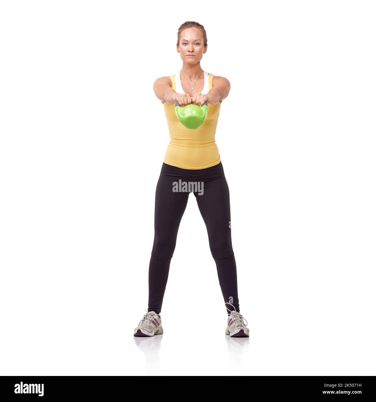 Engaging her glutes. A beautiful blonde woman performing a two-handed kettlebell swing. Stock Photo