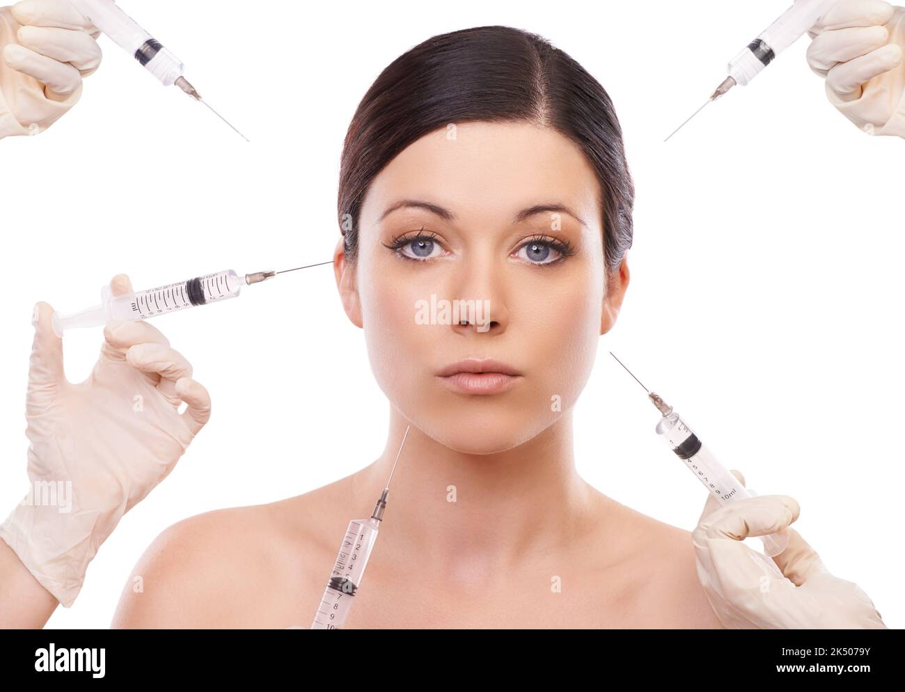 Beauty through botox. A young woman looking at the camera with five injection needle pointed at her face. Stock Photo