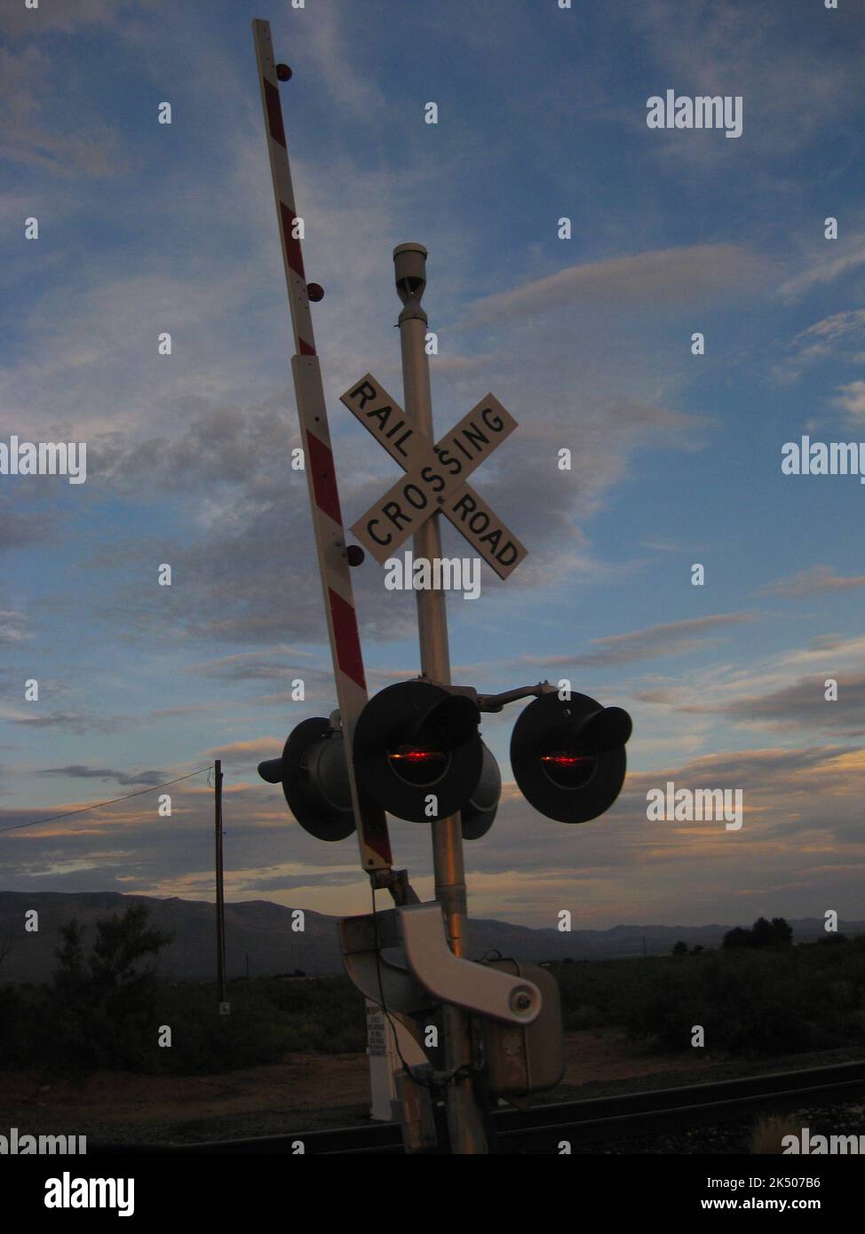 Rural Train Track Crossing Signal at Sunset Stock Photo