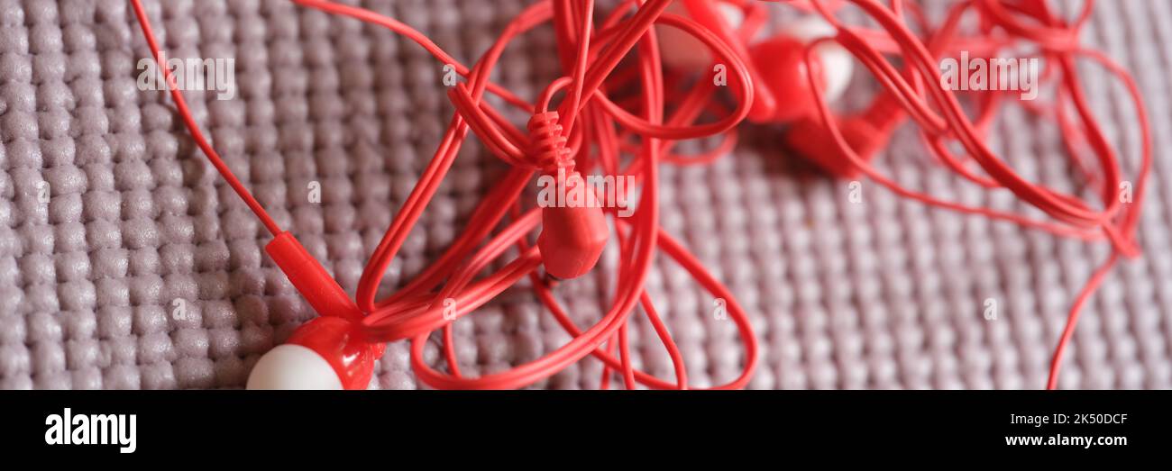 Tangled red headphones on gray background. Headphone mess Stock Photo