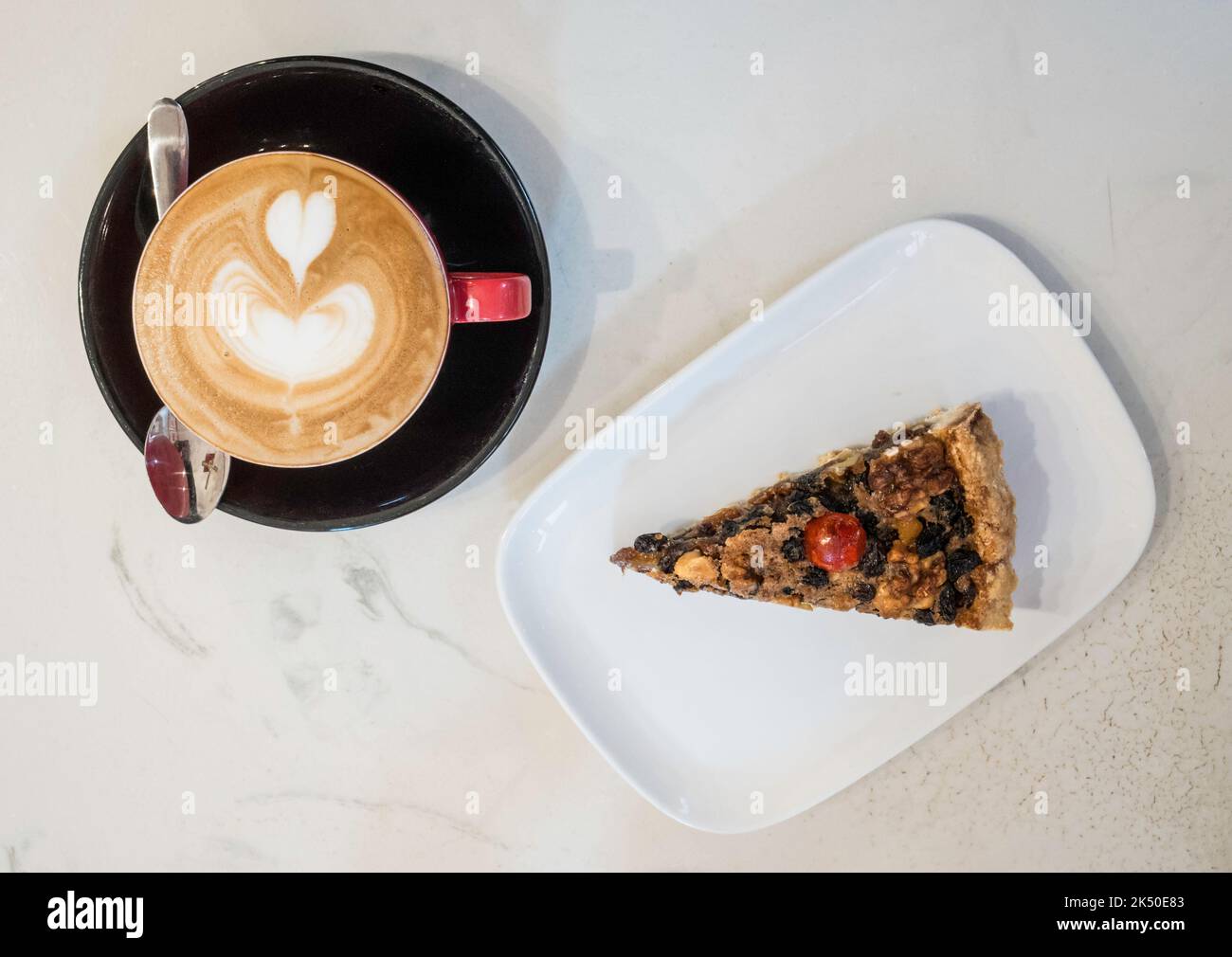 A slice of Ecclefechan Tart on a white plate with a cup of flat white coffee Stock Photo