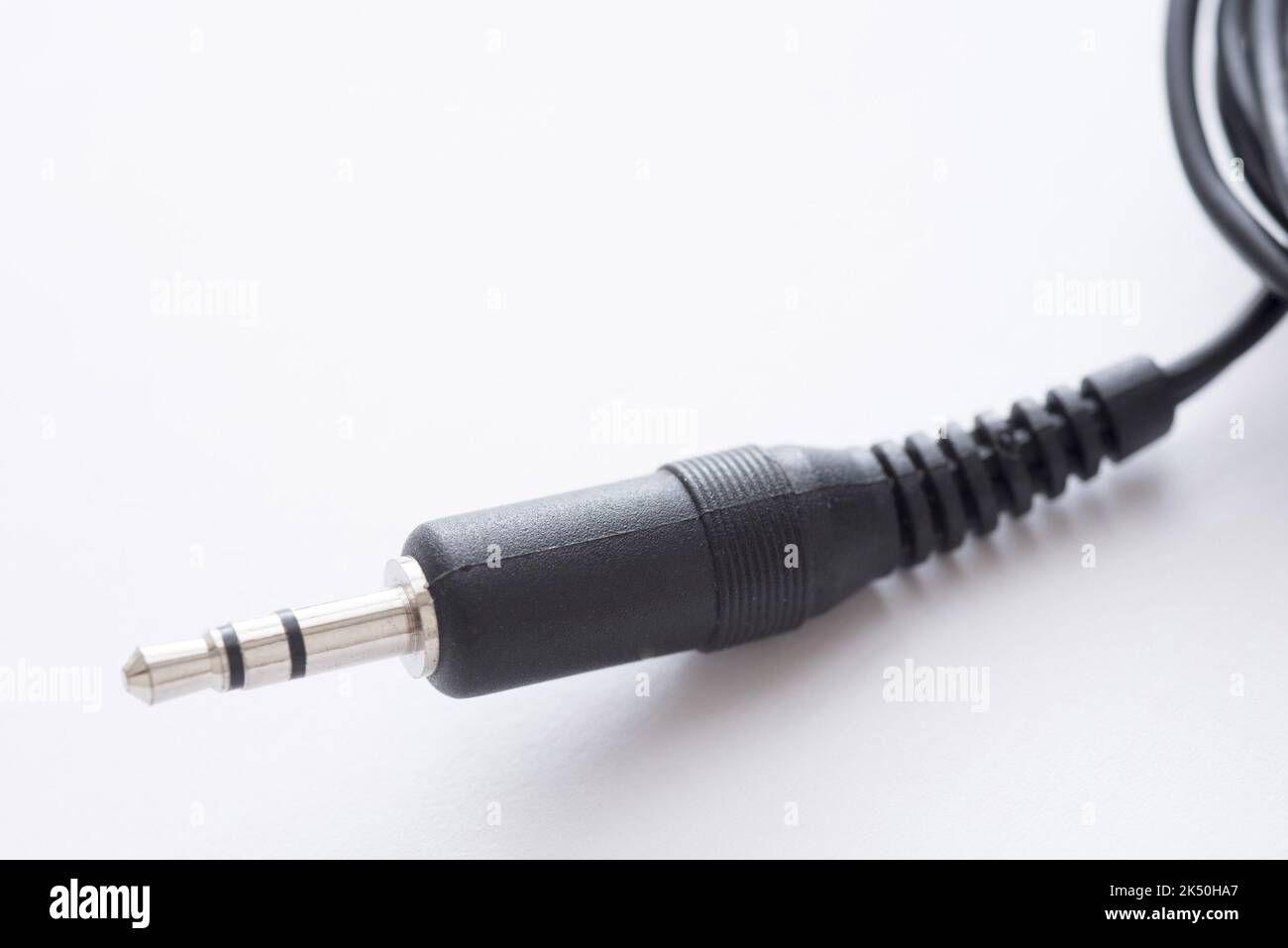 Audio jack 3.5 mm stereo plug with black cord in plastic body close-up on white background with copy space Stock Photo