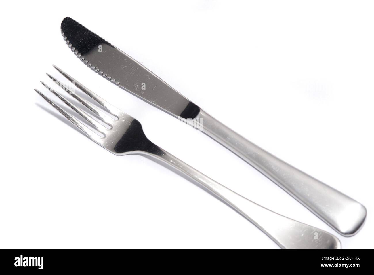 Clean silver metal knife and fork laid out side by side diagonally on