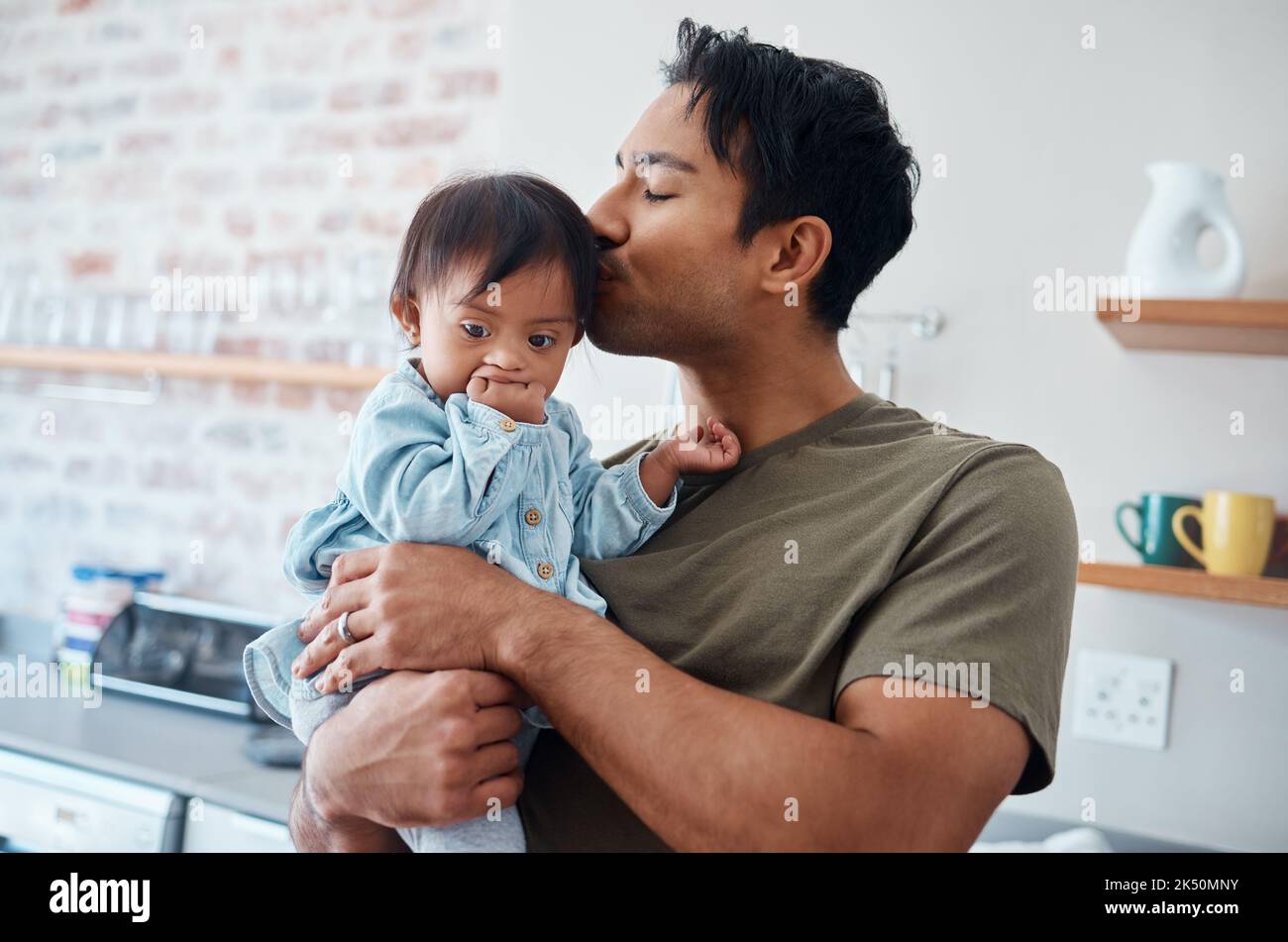 Down syndrome baby bonding with father in their home, kiss and