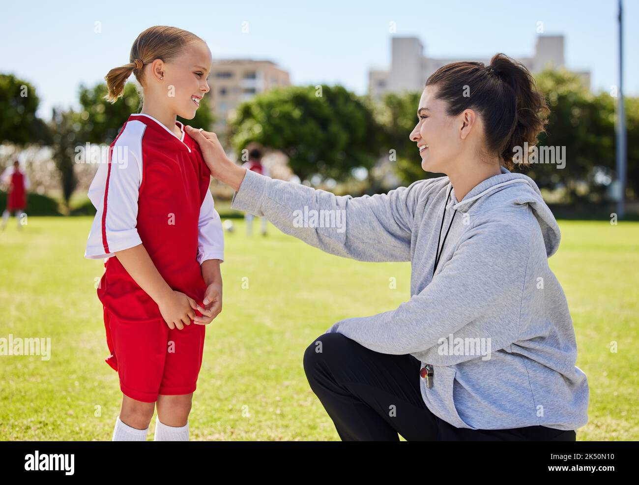 Girl, coach and soccer for motivation, inspiration and help on field for better performance in sport. Woman, child and football together on grass Stock Photo