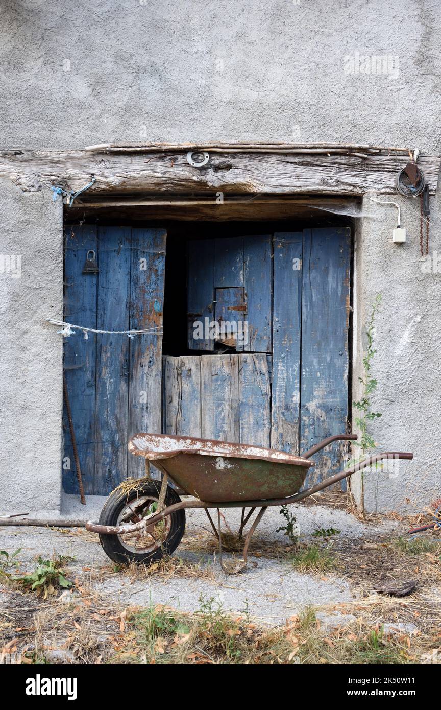 Old Barn Door and Rusty Wheelbarrow Stock Photo