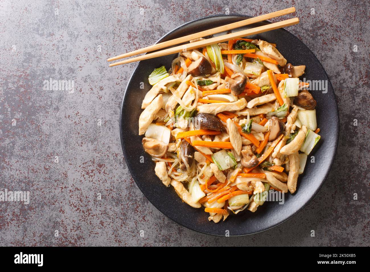 Chop Suey is a quick Chinese American stir-fry with chicken and mixed vegetables in a thick brown sauce close-up in a plate on the table. Horizontal t Stock Photo
