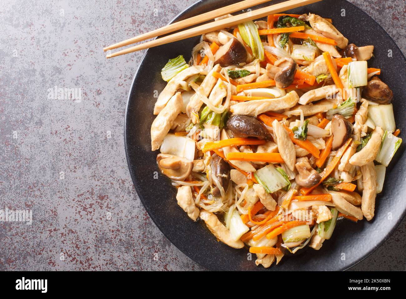 Chop suey made with chicken quickly sauteed with crisp mixed vegetables and bean sprouts in a thick brown sauce close-up in a plate on the table. Hori Stock Photo