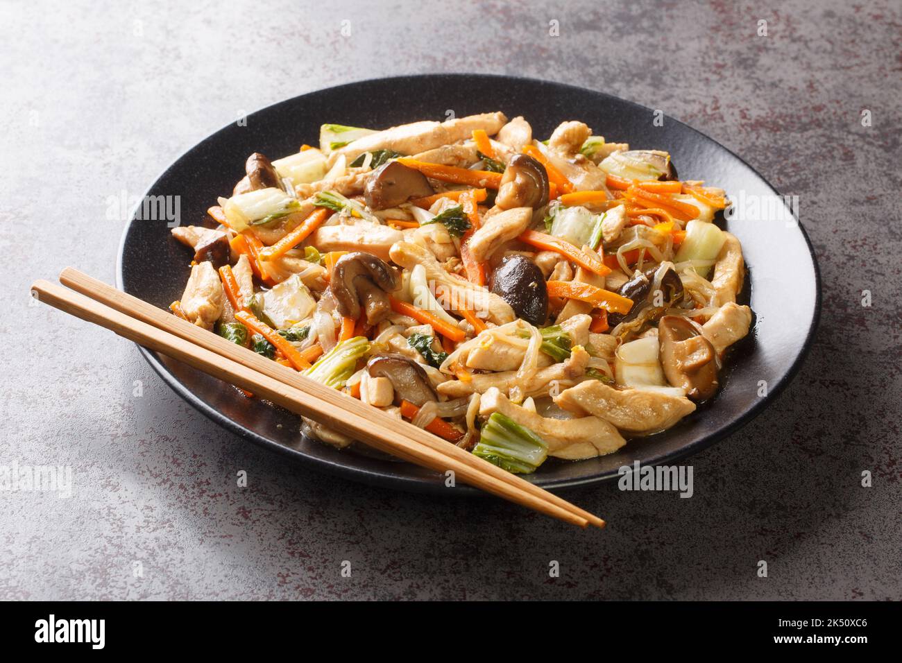 Delicious stir-fry of tender chicken and crunchy vegetables, chop suey close-up in a plate on the table. Horizontal Stock Photo