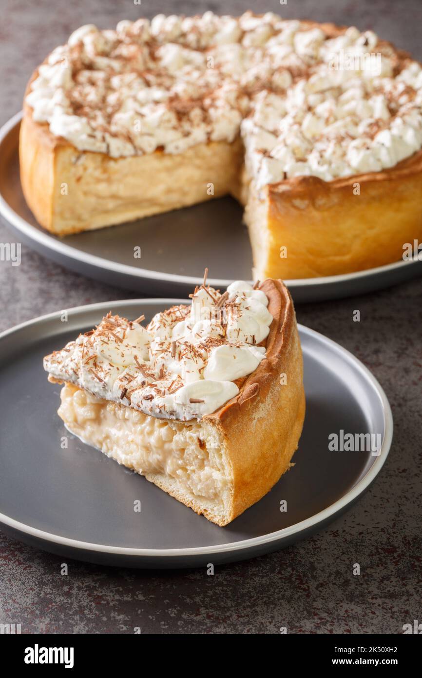 Sweet pie with a filling based on rice pudding topped with whipped cream and chocolate chips close-up in a plate on the table. Vertical Stock Photo