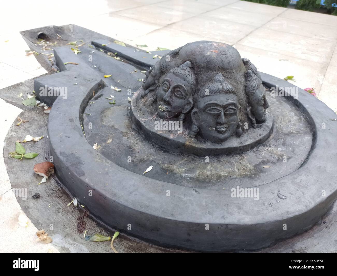 A Shiva linga made with a black stone on plane surface with surrounding made of tiles Stock Photo