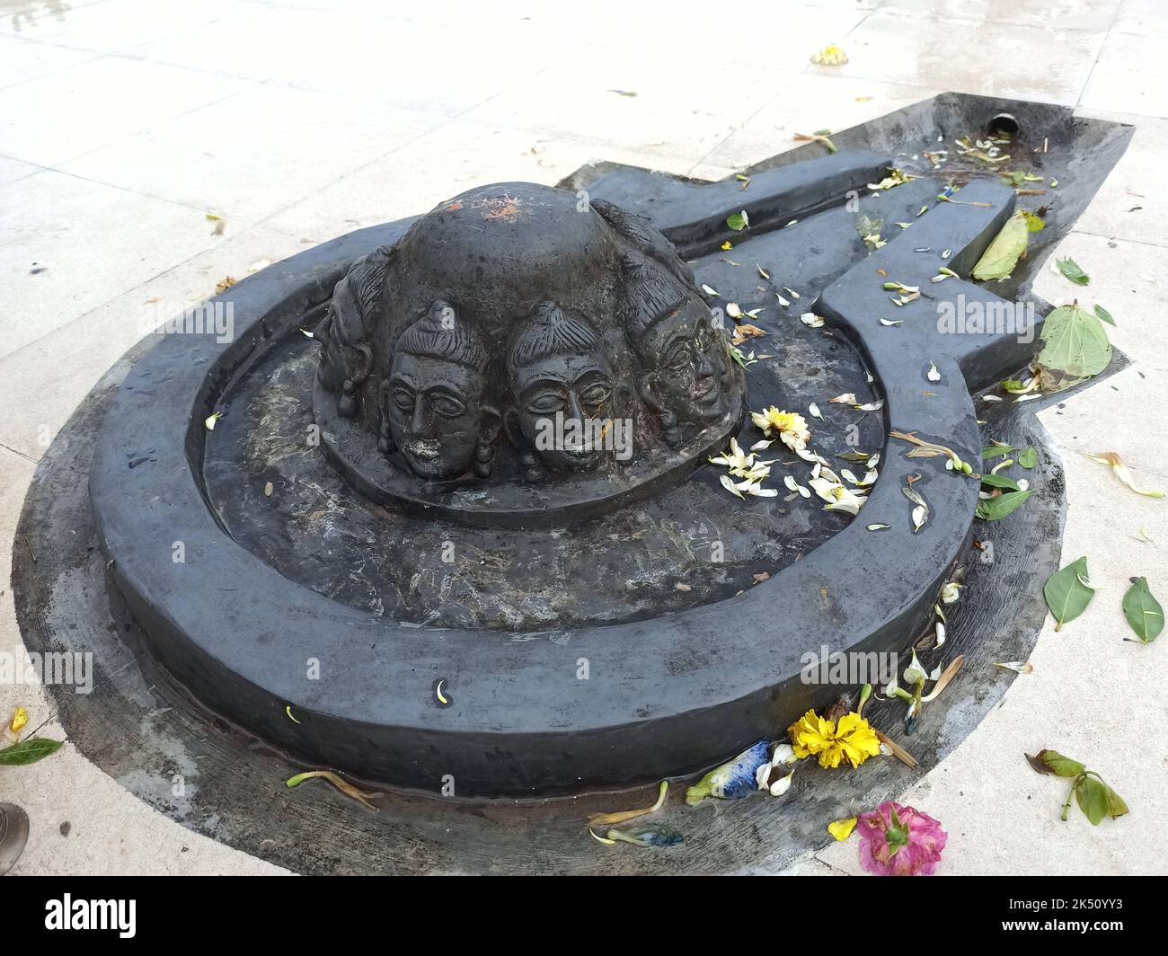 A Shiva linga made with a black stone on plane surface with surrounding made of tiles Stock Photo