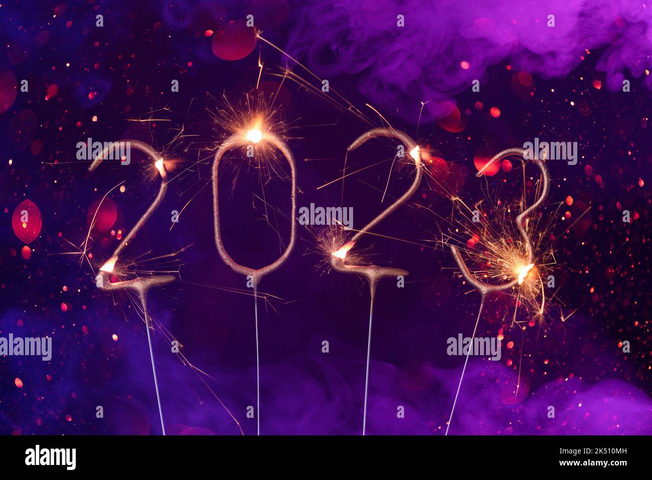 2023 Happy new year Silvester greeting card banner with burning golden sparklers shiny glitter bokeh and colorful smoke Stock Photo