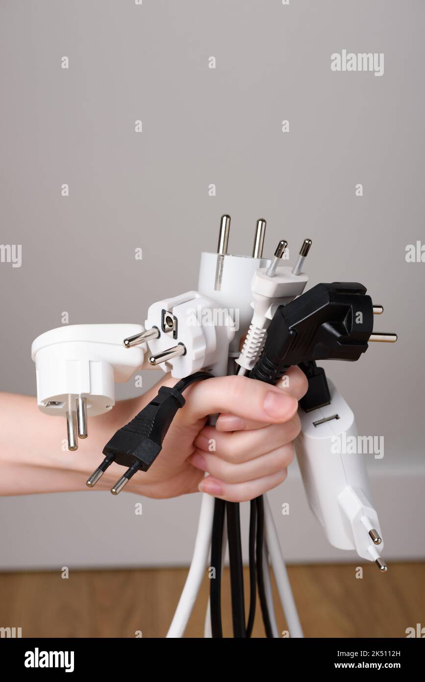 Woman hand holding bunch of electric plugs. Electric power consumption or rising electricity price concept Stock Photo