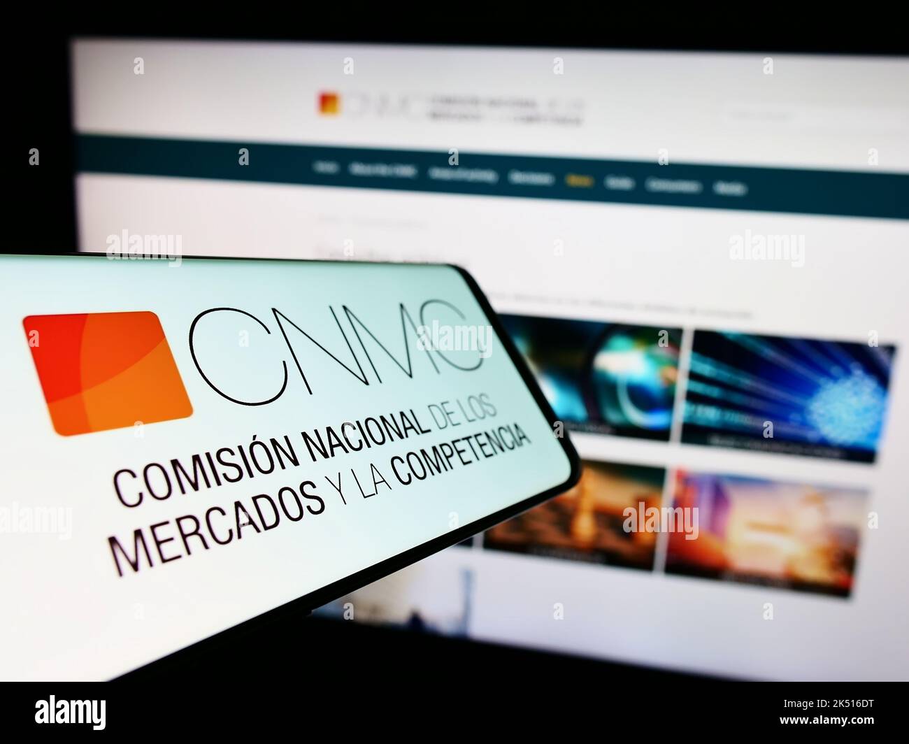 Mobile phone with logo of Spanish competition regulator CNMC on screen in front of business website. Focus on center-left of phone display. Stock Photo