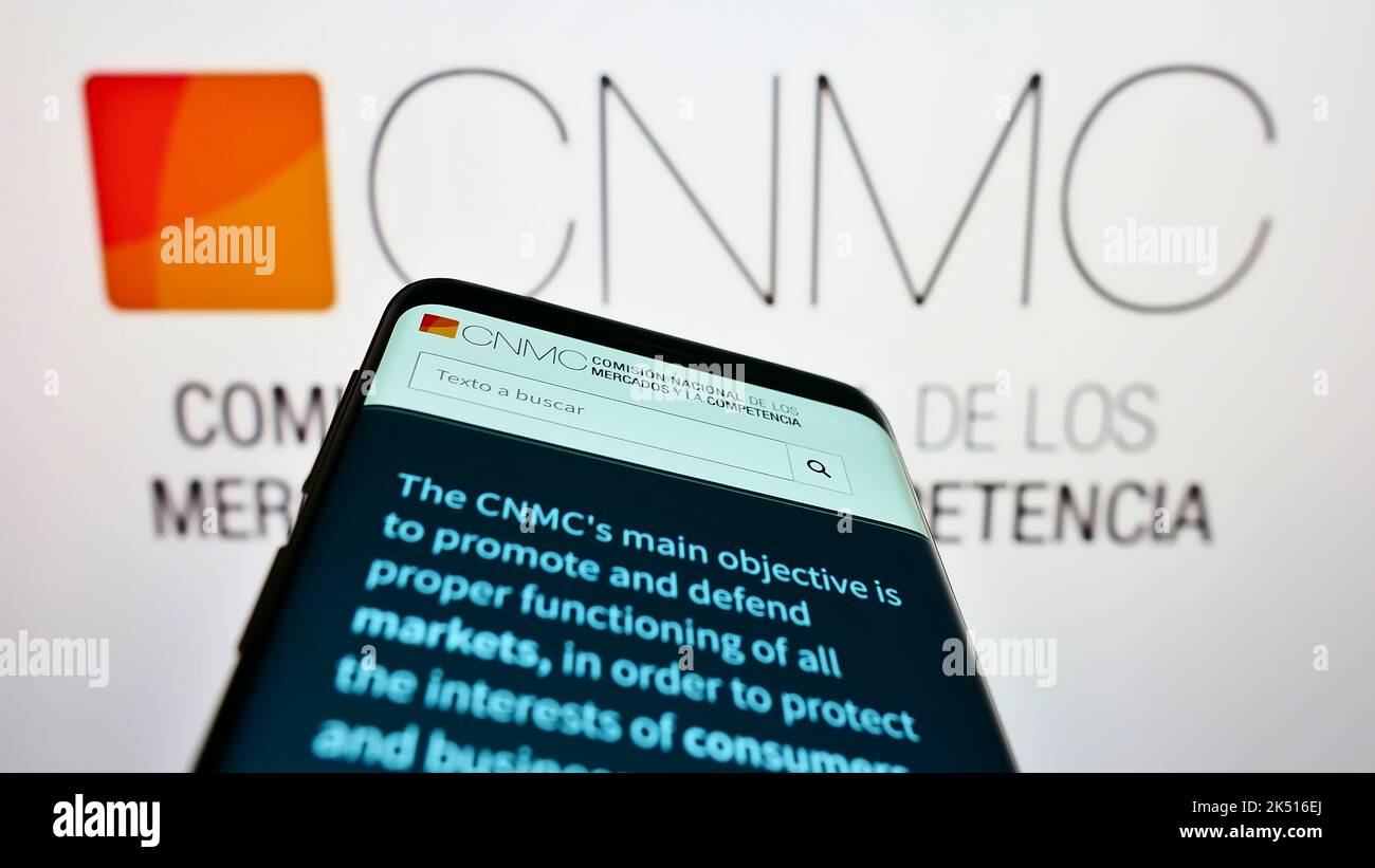Smartphone with website of Spanish competition regulator CNMC on screen in front of logo. Focus on top-left of phone display. Stock Photo