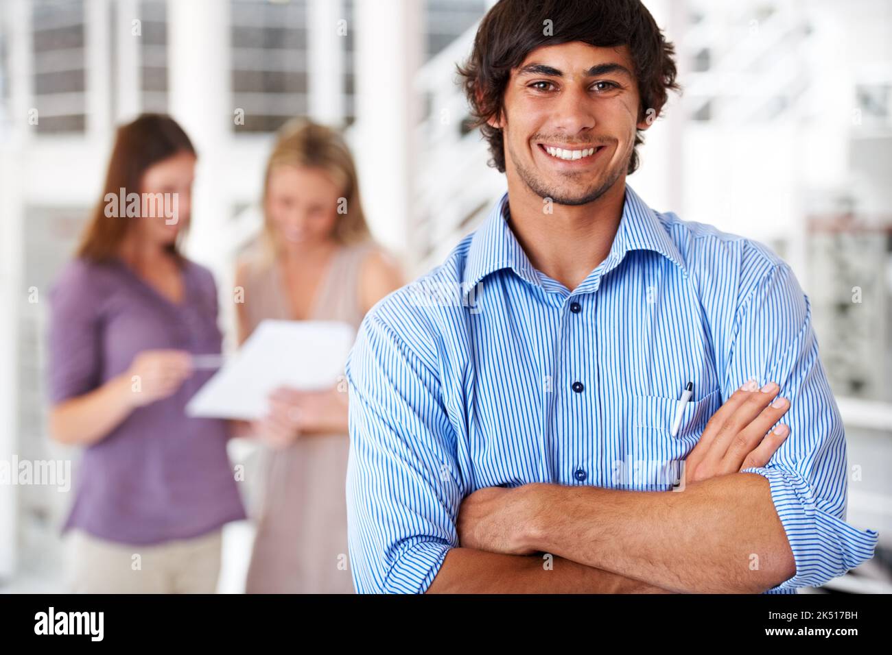 Im taking my team to the top. a leader smiling at the camera with colleagues blurred in the background. Stock Photo