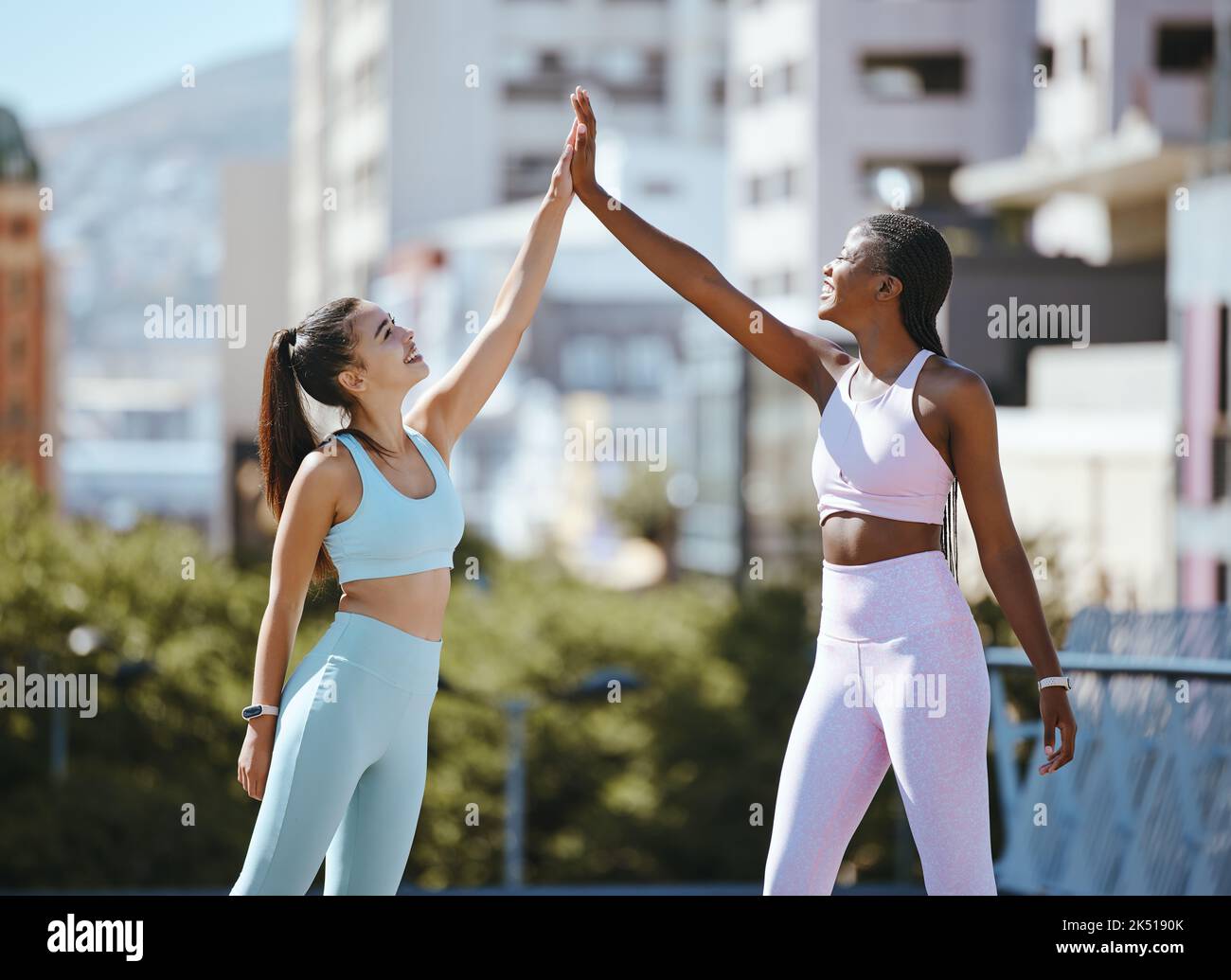 Fitness, women and friends high five after running, training and cardio workout success together outdoors in summer. Winners, sports and happy runners Stock Photo