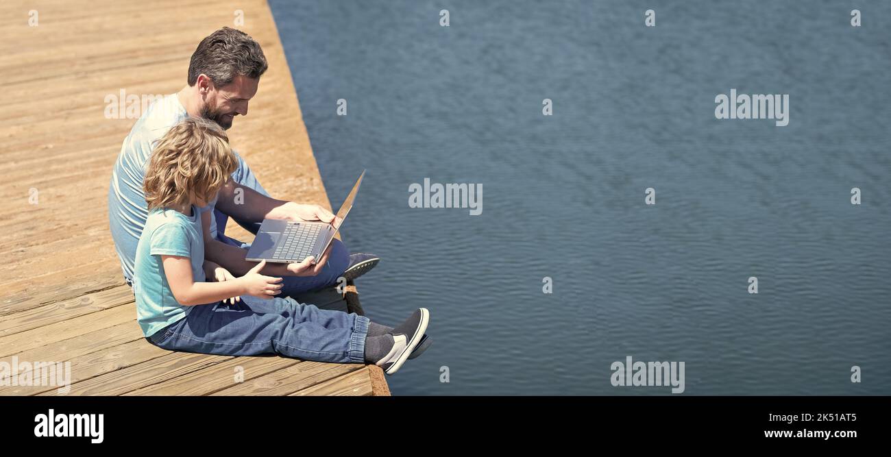 Banner of father and son take your e-Learning on summer holidays. Father and son use laptop. Engaging family in e-Learning Stock Photo