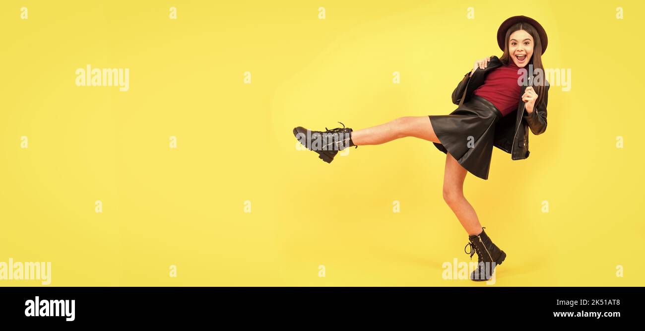 happy teen girl in hat and leather clothes making wide step forward, copy space, having fun. Child face, horizontal poster, teenager girl isolated Stock Photo