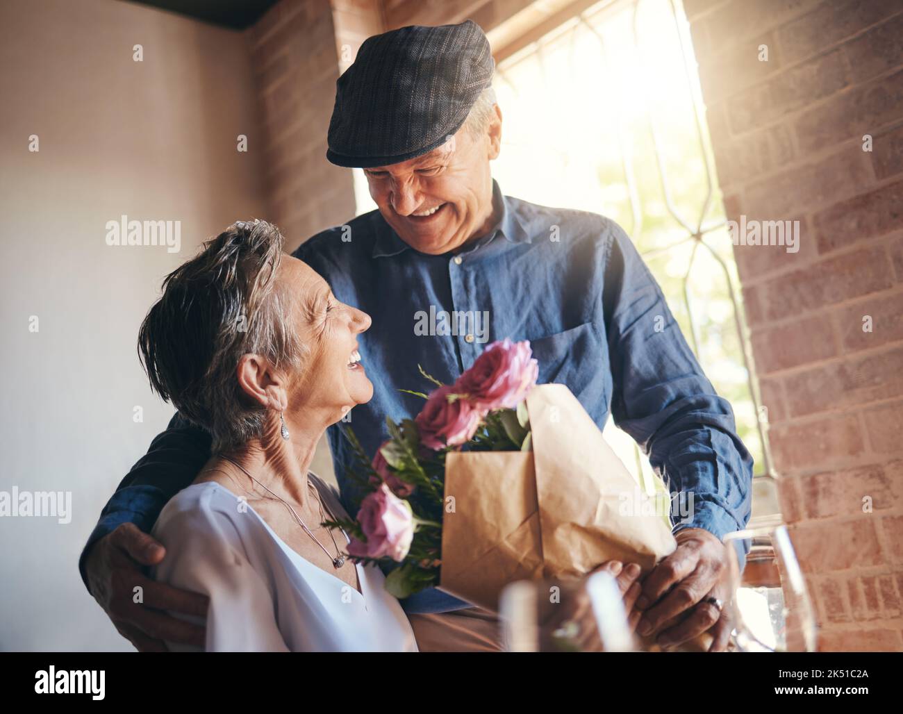 Love, flowers and gift of a senior couple in celebration, joy and happiness of a birthday, anniversary or milestone. Elderly man and woman, happy Stock Photo