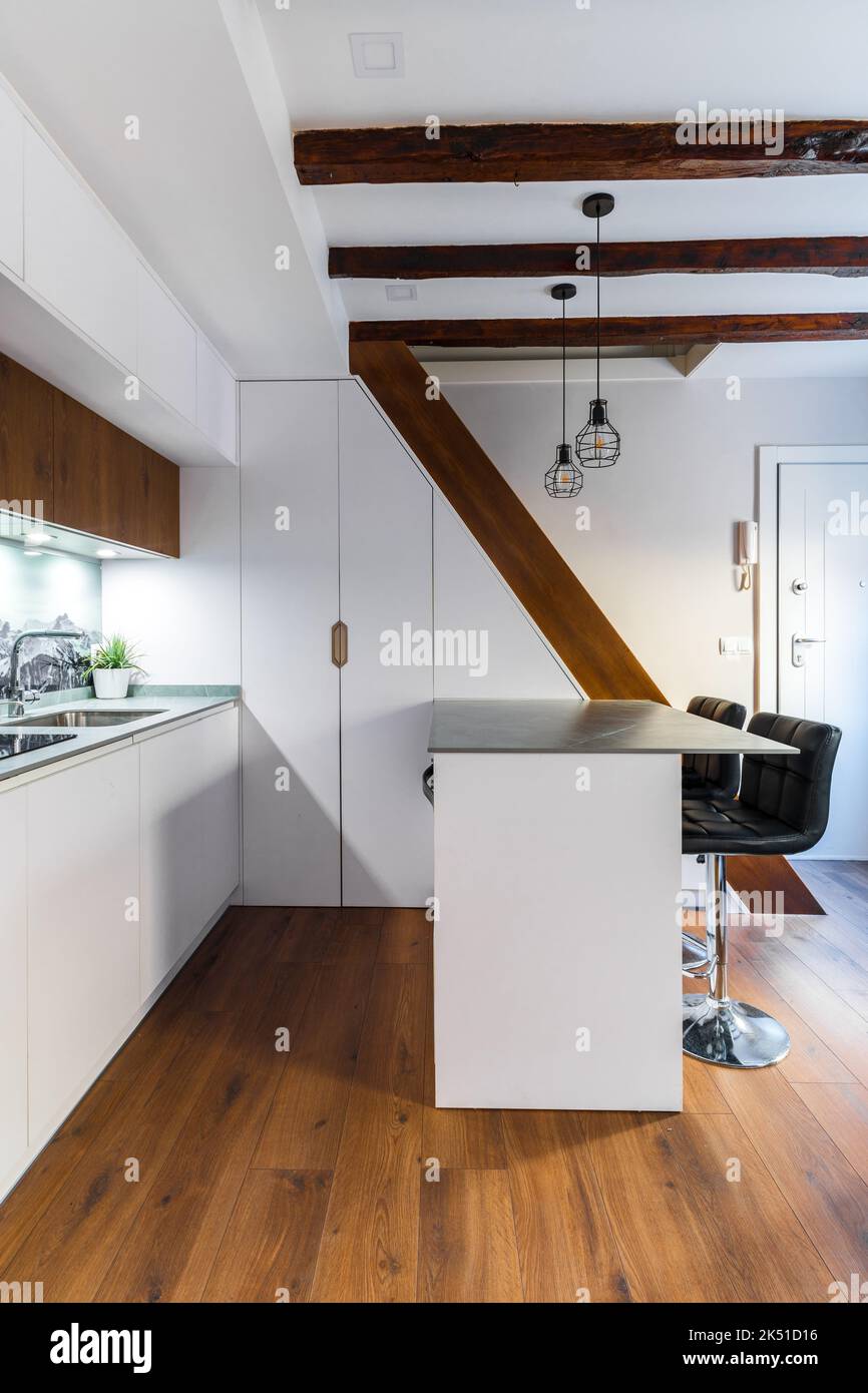 White cabinets placed in kitchen in modern apartment with wooden ...