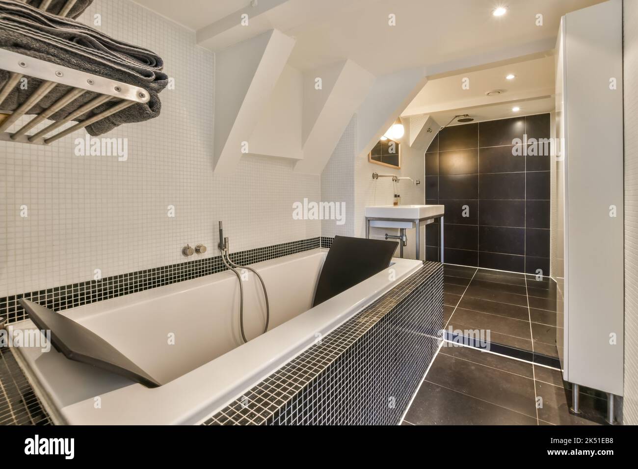 White ceramic bathtub and toilet bowl in illuminated bathroom with