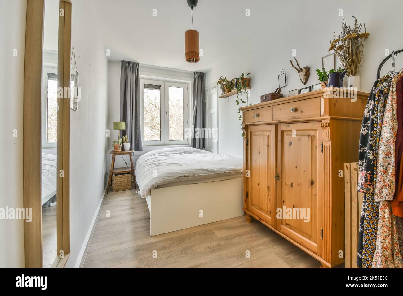 Contemporary bedroom interior with lamp above bed next to wardrobe on parquet in house Stock