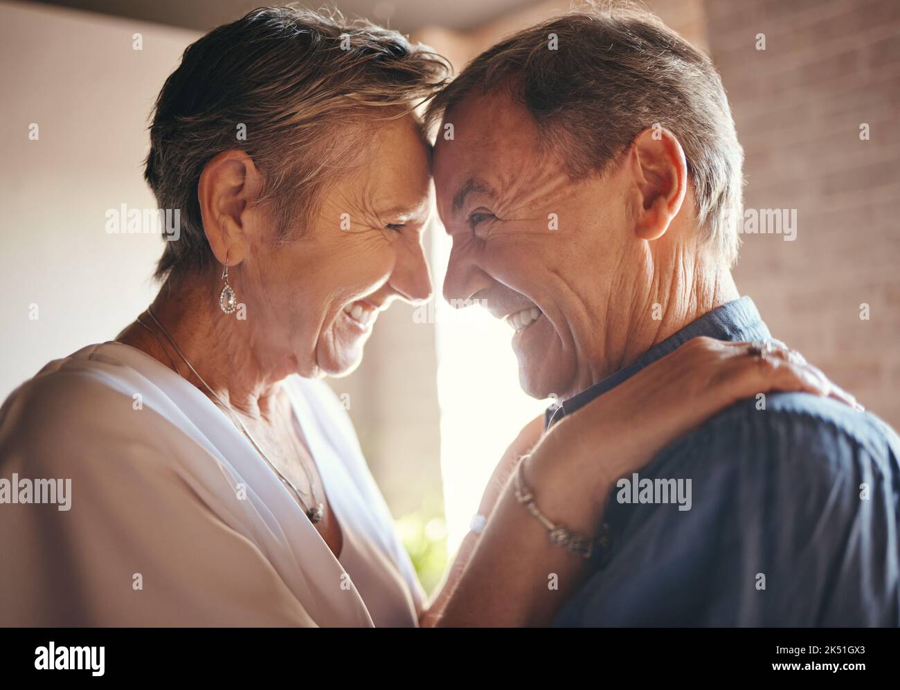 Love, happy and laugh elderly couple hug and bond in their home together, cheerful and sharing a funny joke. Humour, care and affection by senior man Stock Photo