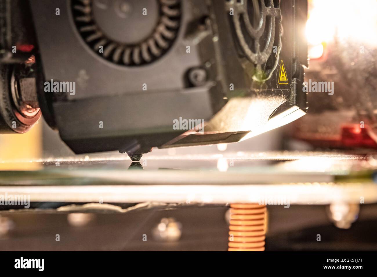 Close-up of a worn Ender 3 Max stock print head with strong warm backlight in z-offset leveling setting. Stock Photo