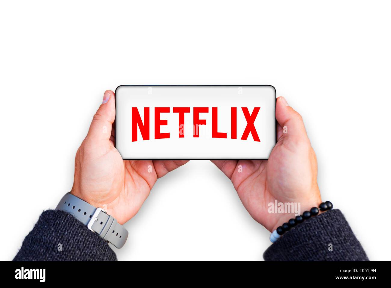 Belgrade, Serbia - October 05, 2022: Holding smartphone in hands with Netflix logo on screen. Netflix is TV show and movie streaming service Stock Photo