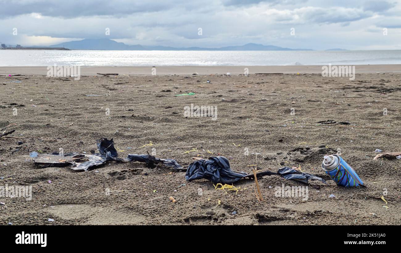 Micro plastics debris and used spray cans pollution on sea coast ecosystem,environmental waste damage Stock Photo