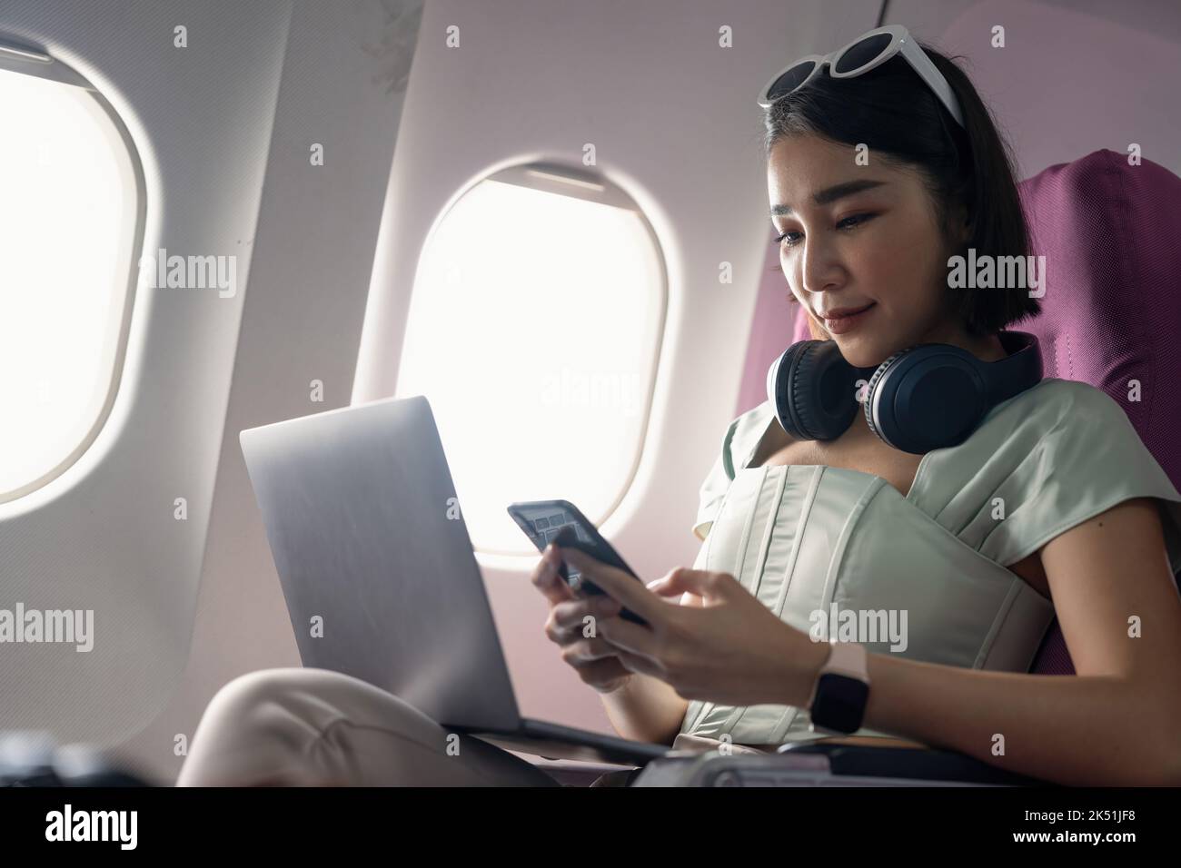 Attractive asian woman passenger of airplane read news from networks via smartphone and wifi on board. tourism traveler concept. Stock Photo