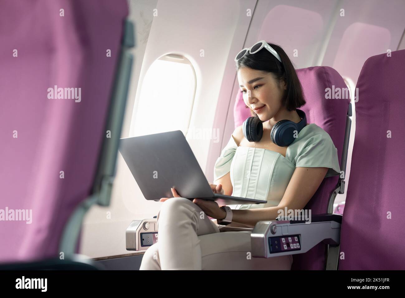 Attractive asian woman passenger of airplane using laptop computer and wifi on board. tourism traveler concept. Stock Photo