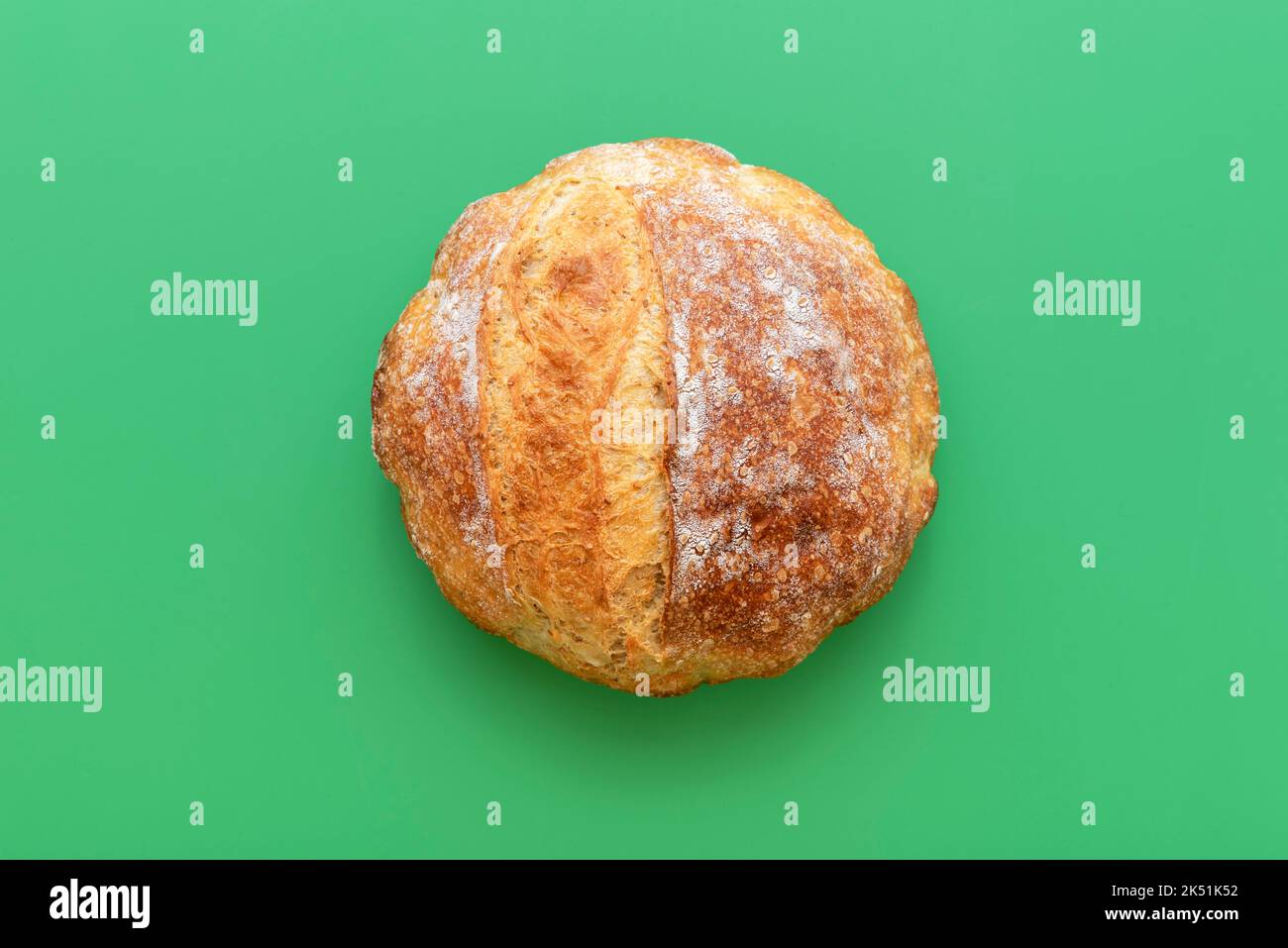 Homemade bread minimalist on a green background. High-angle view with delicious white bread with a golden crust. Stock Photo