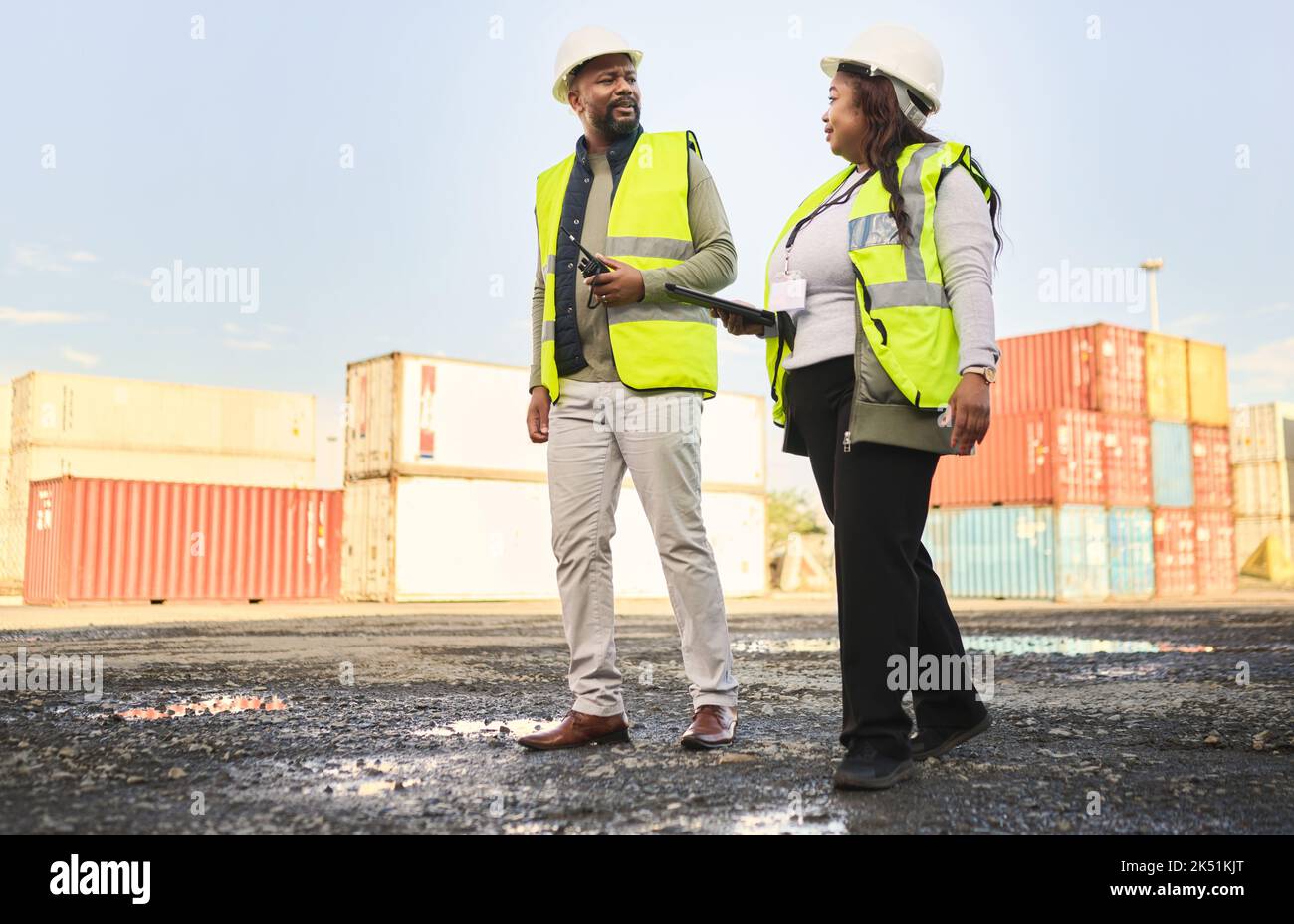 Logistics, supply chain and engineer team in shipping cargo industry walking, talking and doing inspection on shipyard. Black man and woman in Stock Photo