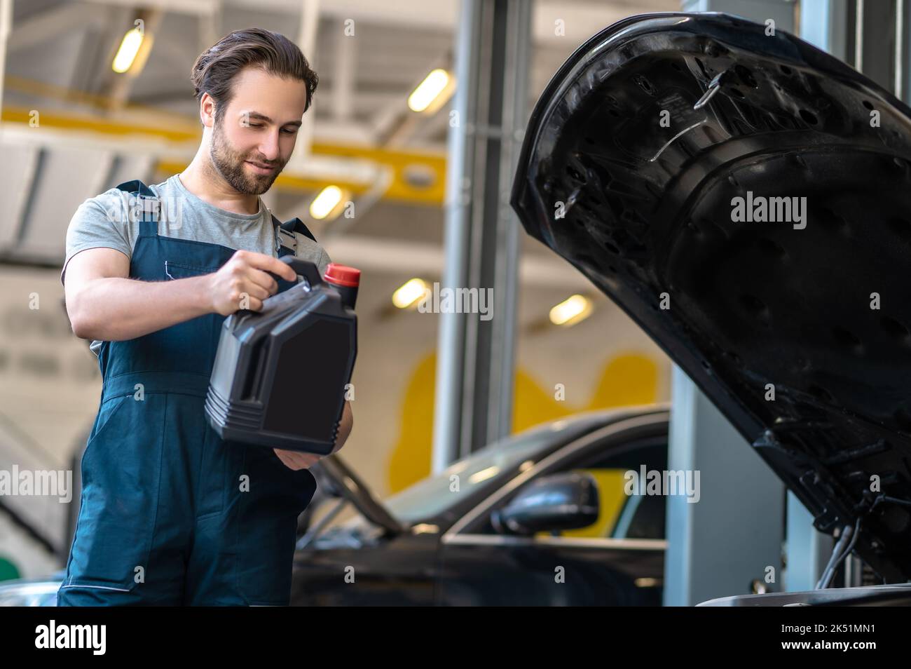 Young automotive technician performing the engine oil change Stock