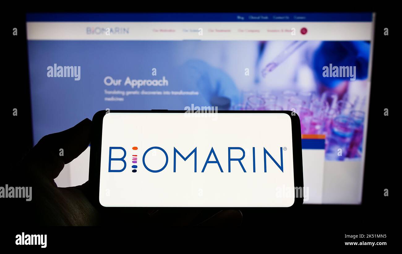 Person holding smartphone with logo of US company BioMarin Pharmaceutical Inc. on screen in front of website. Focus on phone display. Stock Photo