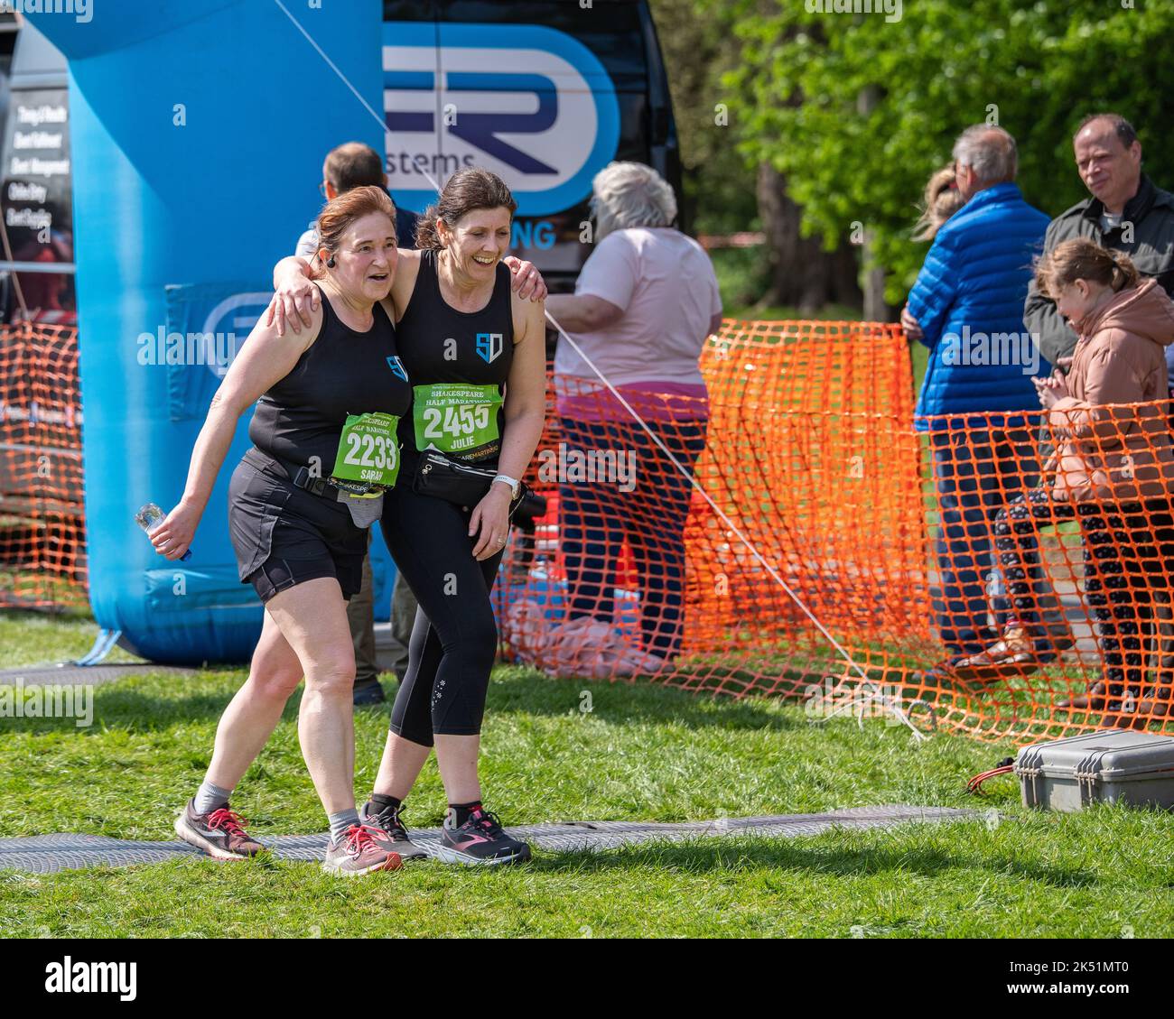 Shakespeare Marathon and Half Marathon. Exhausted but happy women runners helping each other at the finish line. Stock Photo