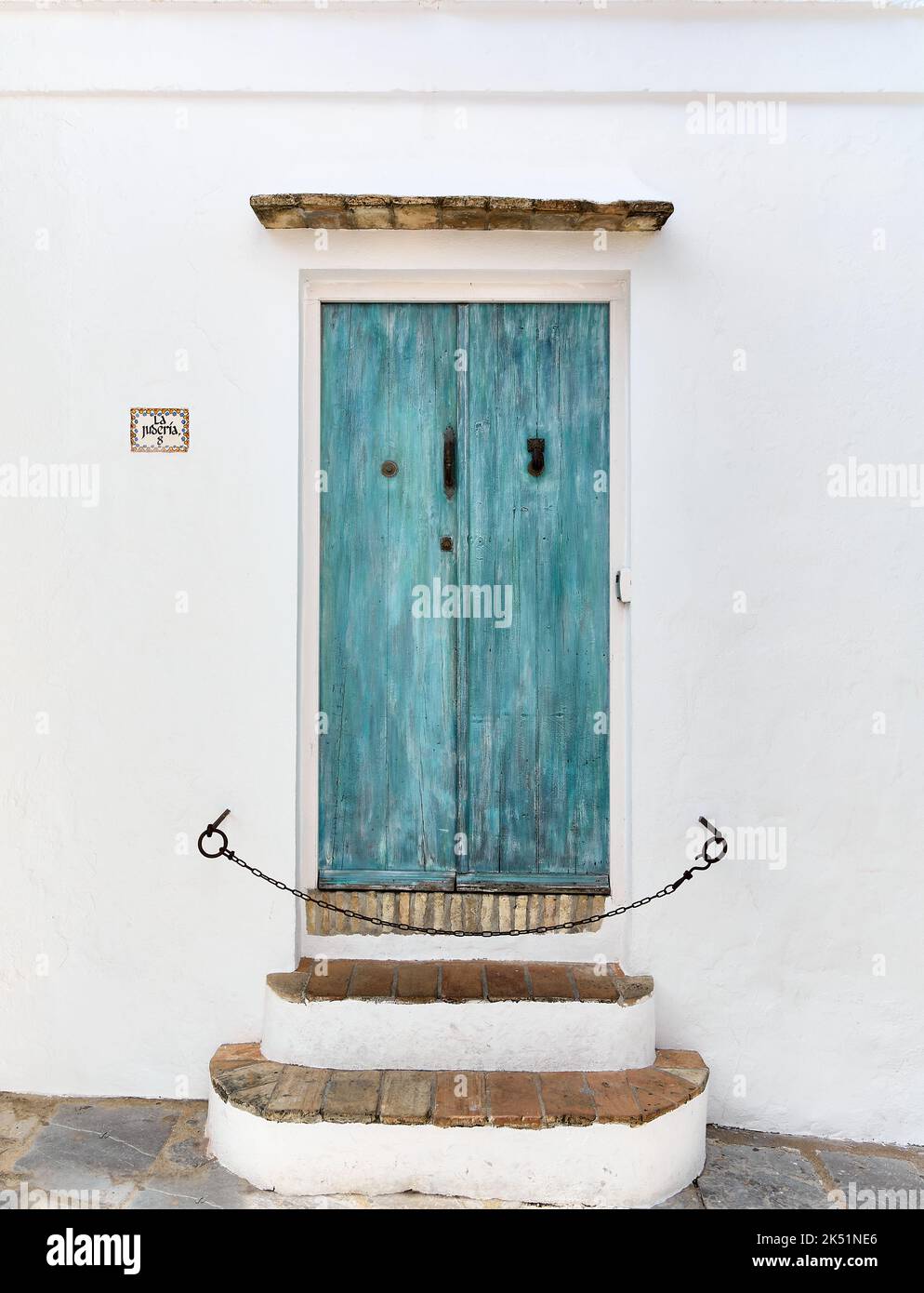 Old wooden door painted in blue with white facade Stock Photo