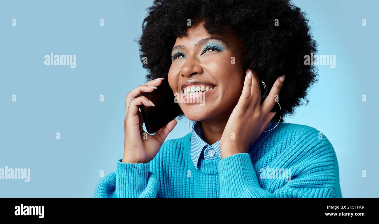 Black woman, talking on smartphone and smiling on blue background in ...