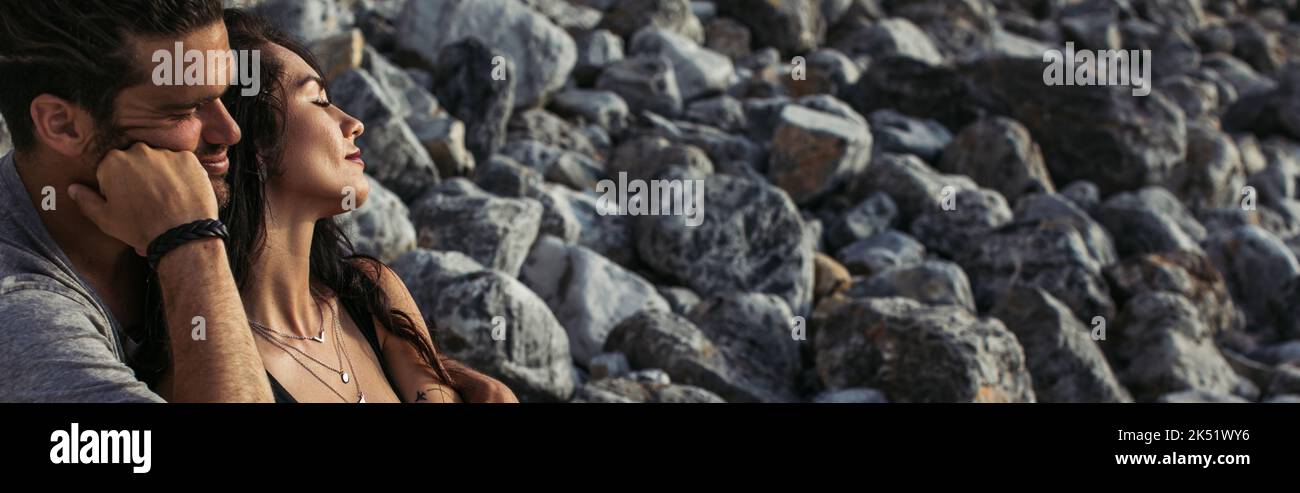 Man Hugging Rocks bearded man hugging tattooed woman with closed eyes near rocks on beach ...