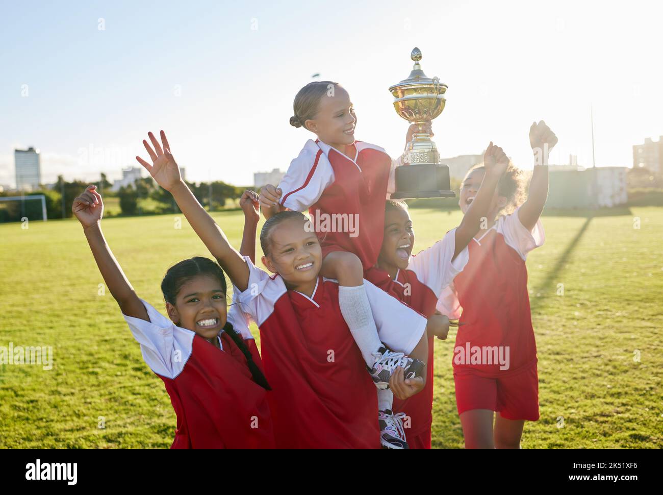 Sports. soccer and young girls with trophy celebrate, happy and excited outside on field for their victory. Team, players and female children are Stock Photo