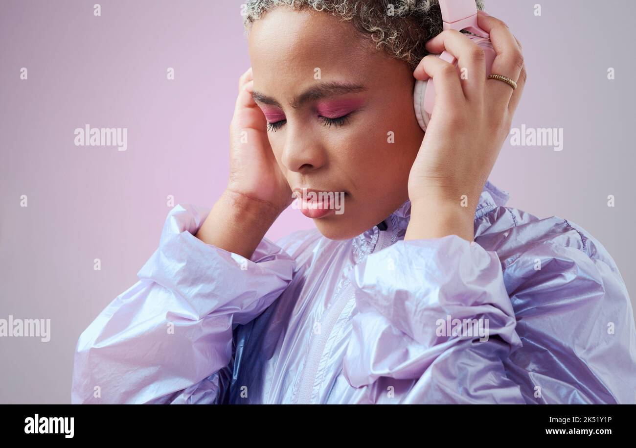 Fashion, headphones and black woman listening to music with retro vaporwave clothes on studio pink background. Gen z girl model with color cosmetics Stock Photo