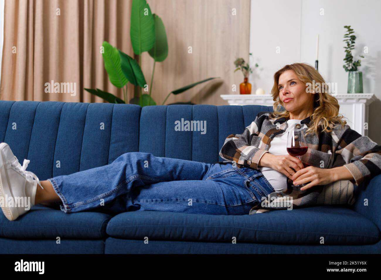 Woman relaxing with glass of red wine watching television Stock Photo ...